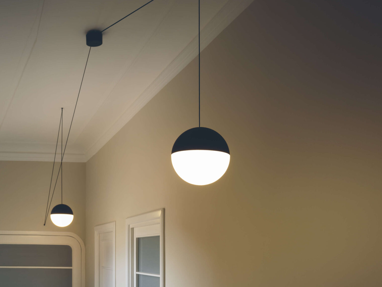 Minimalist lighting fixture designed by Michael Anastassiades for Flos, featuring a glowing sphere on an extended black cable.