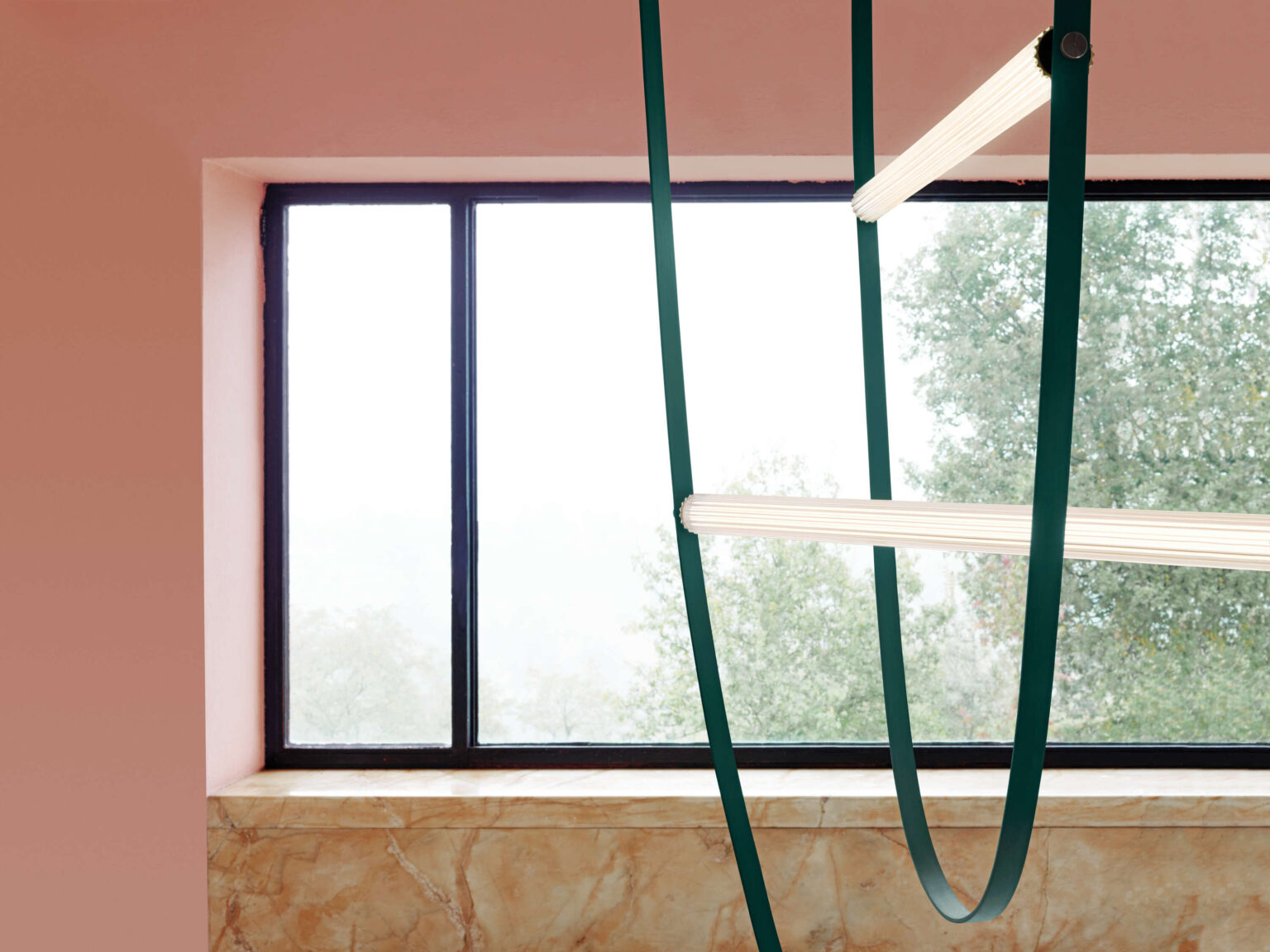 Wireline pendant lamp in forest green, installed in a modern interior, casting soft, diffused light over a dining area.