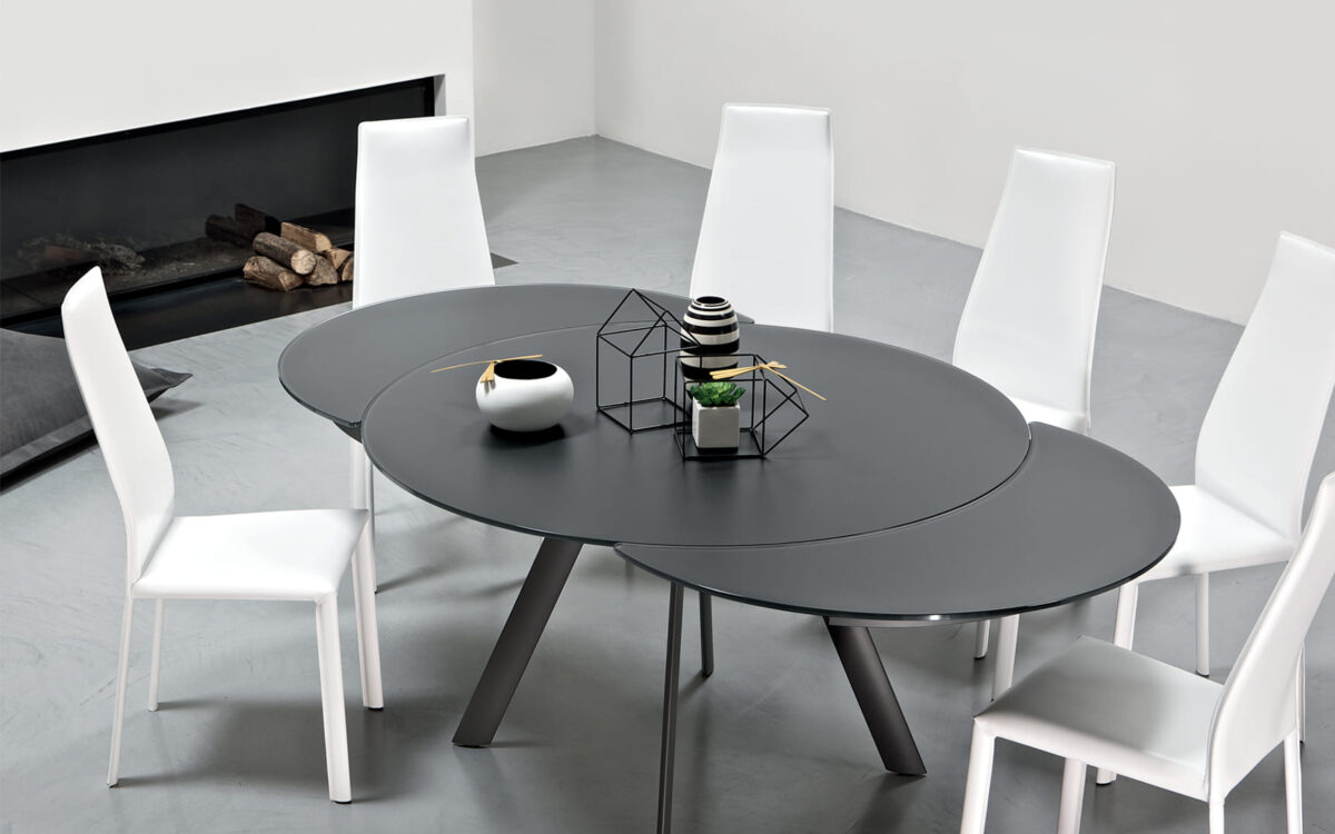 Close-up of Tour by Bontempi showing the tapered metal column base in aged-brass finish under a polished crystal tabletop.