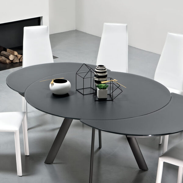 Close-up of Tour by Bontempi showing the tapered metal column base in aged-brass finish under a polished crystal tabletop.