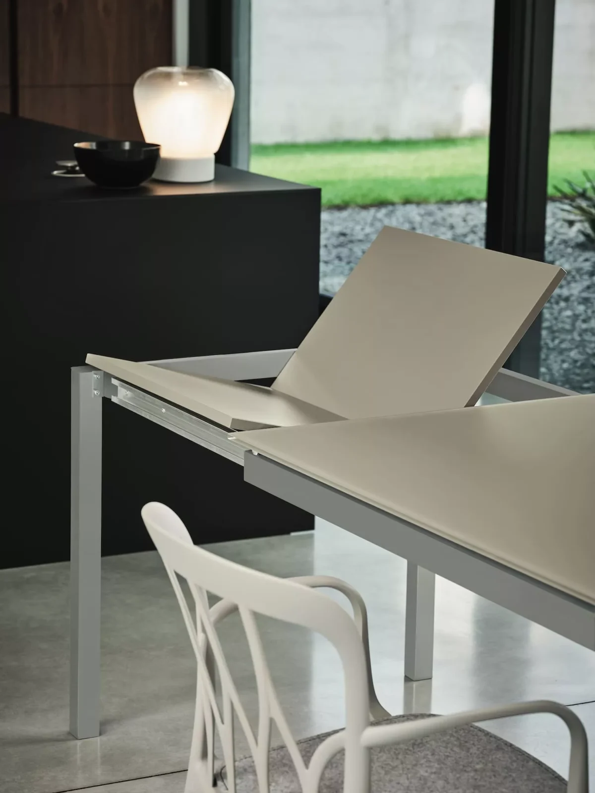 Close-up of Mango table's scratch-resistant velvet matt anti-scratch lacquered glass top and sturdy metal base.