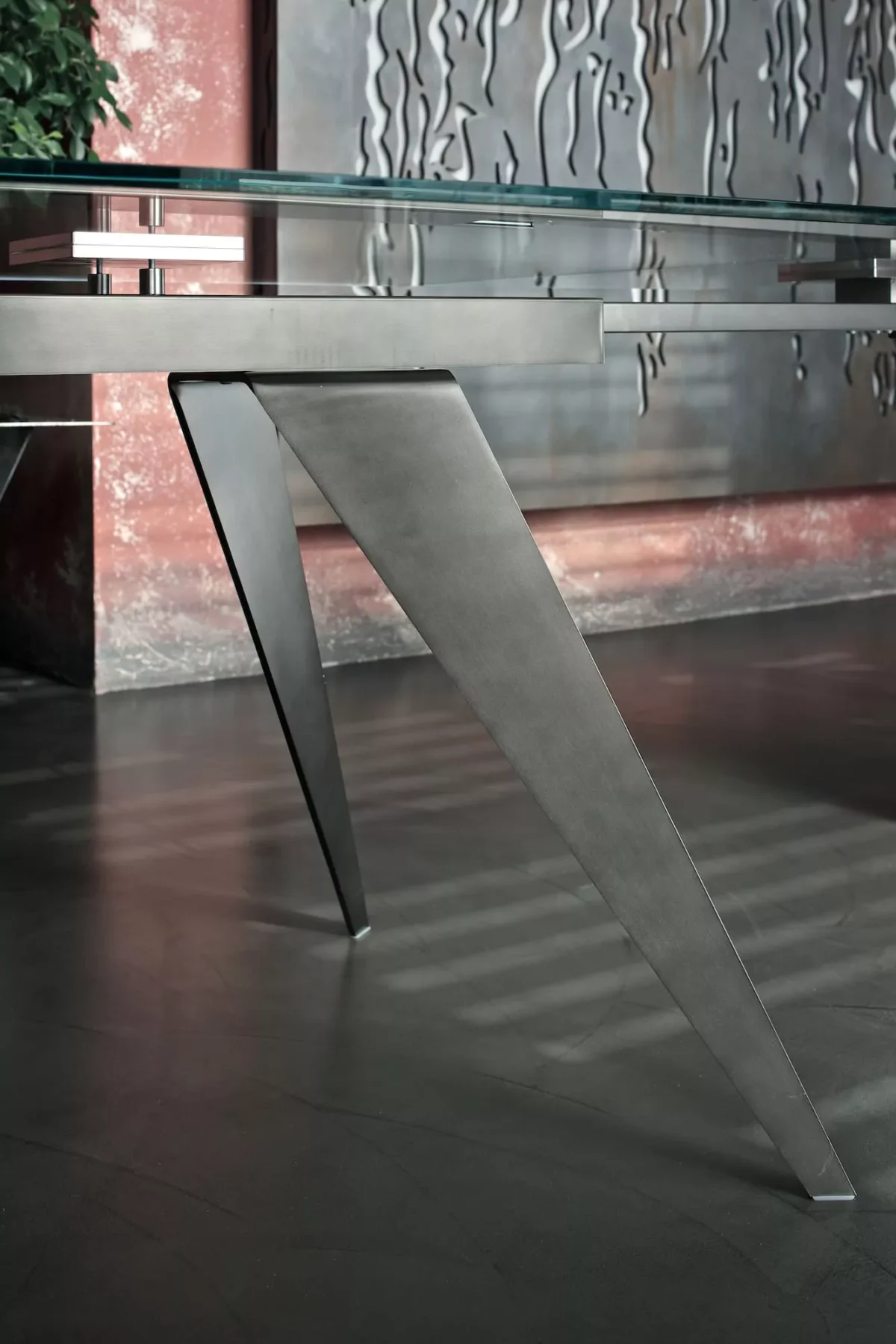 Close‑up of Ramos by Bontempi highlighting its tapered metal blade legs and matt black velvet‑glass tabletop.