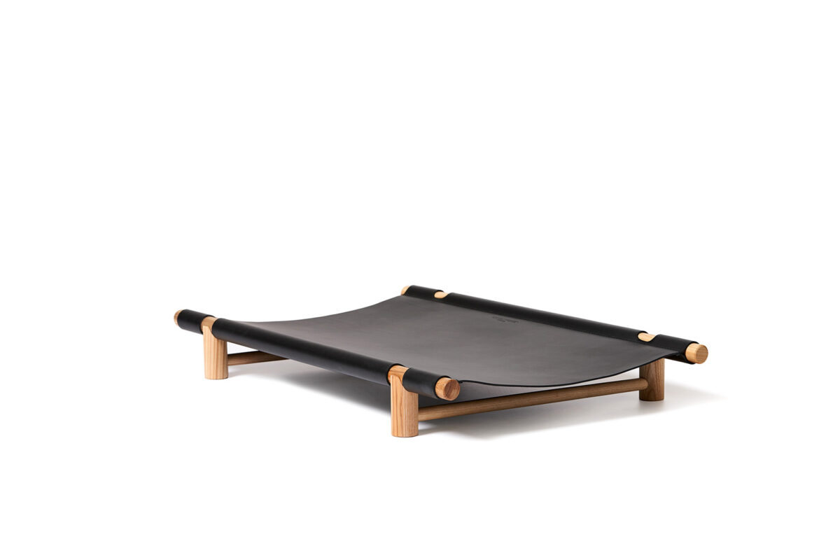 Berberé transportable dog bed by Opinion Ciatti in black leather, featuring a solid ash wood frame and waterproof leather hammock, displayed in Royal Oak, Michigan showroom.