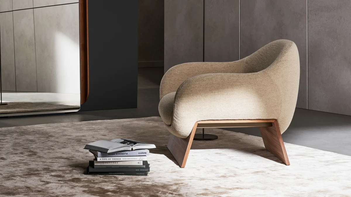 Contemporary Bonaldo Boolean armchair showcasing soft curvy profile atop solid wood bridge base in Canaletto walnut