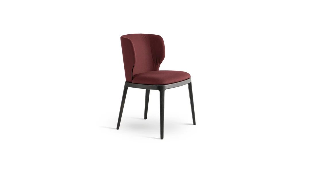 "High‑back Joy chair upholstered in leather, supported by durable solid wood legs in walnut finish."
