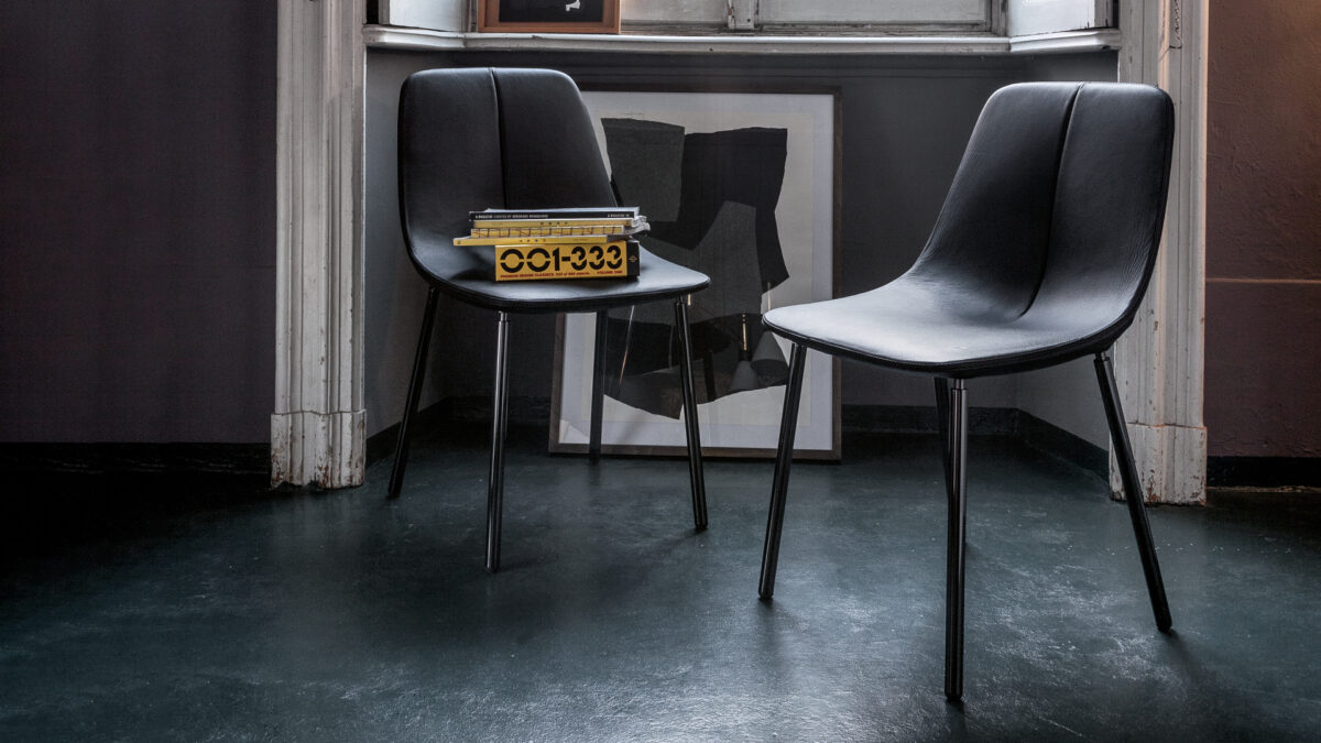 "Front view of By Met chair highlighting its elegant padded backrest and minimalist metal base."