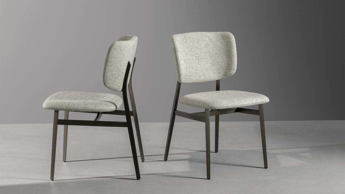 "Contemporary Noor chair with light and solid painted metal legs, cushioned fabric seat, and open‑back design."