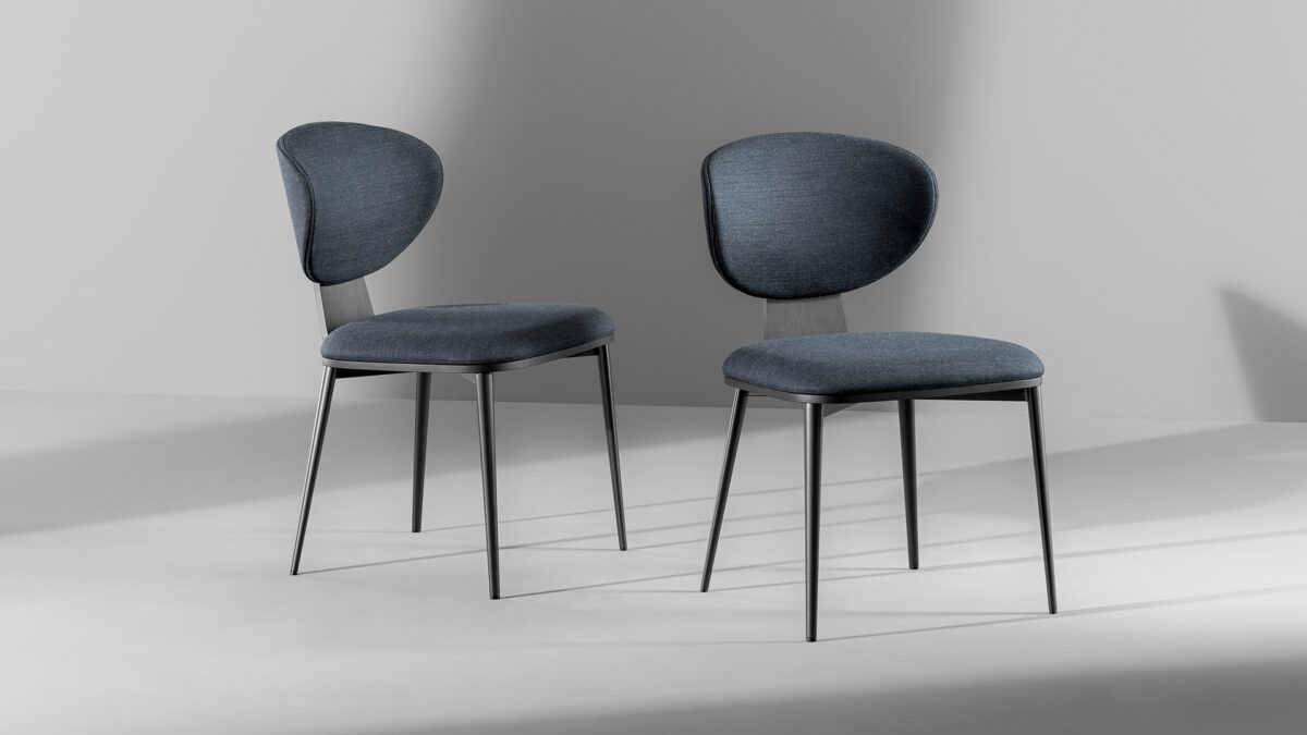 "Side view of Olos chair showing smooth curved wooden frame and soft fabric upholstery."