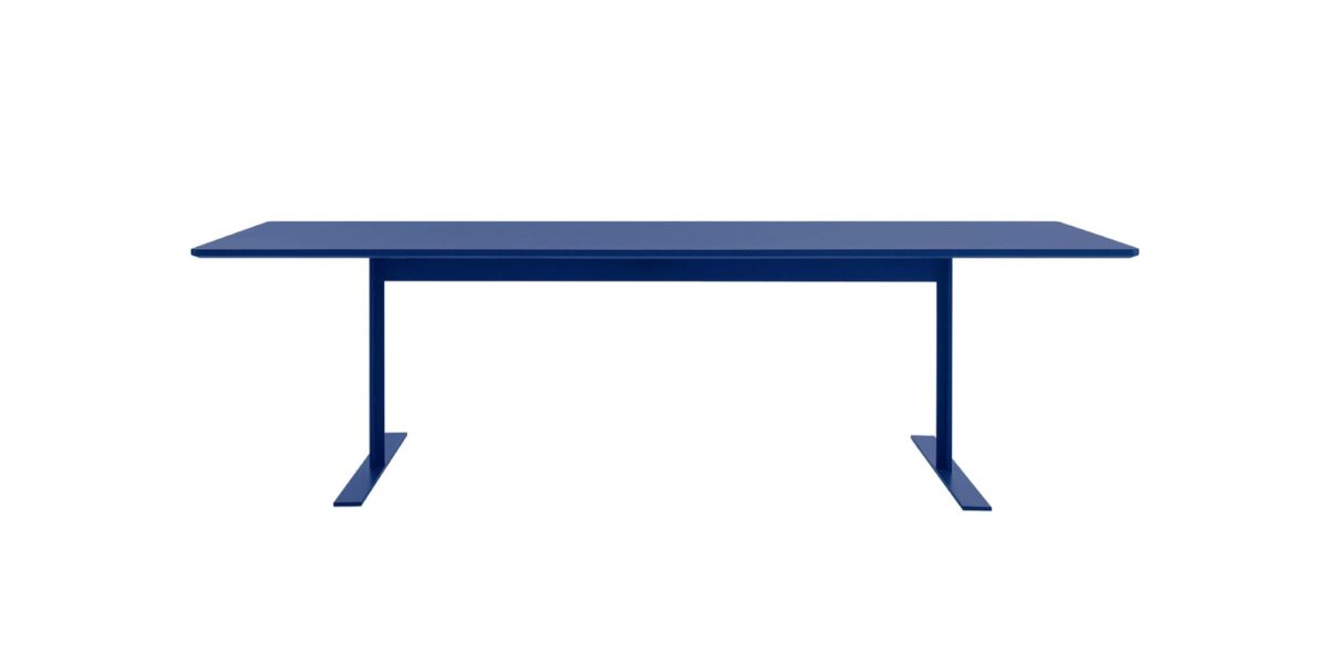 “Detail image of white-lacquer Luxor Table’s metal feet and wood-fibre top in an airy contract space.”