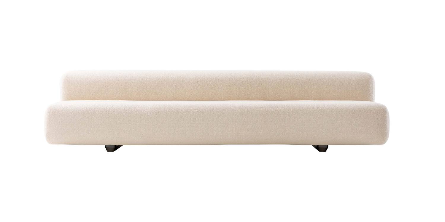 “Three-quarter view of Big Sofa under pergola, its plush upholstery contrasting with polished chrome legs in an outdoor-adjacent lounge setting.”