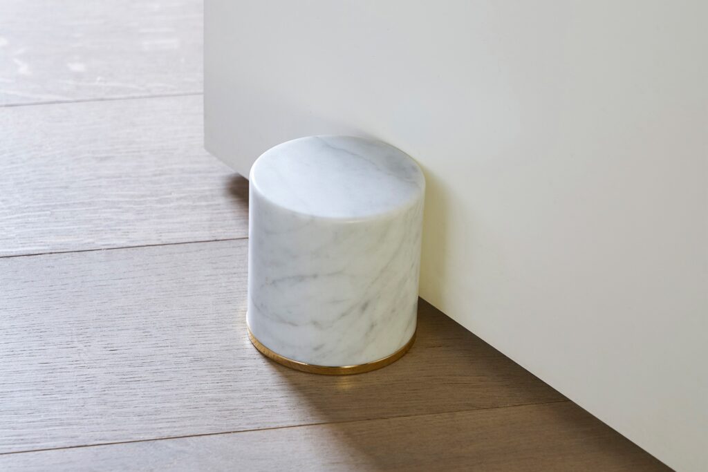 Fermaporte by Opinion Ciatti, a cylindrical white Carrara marble doorstop with a 24K gold-plated steel ring, adds a touch of luxury to contemporary interiors in Royal Oak, Michigan.
