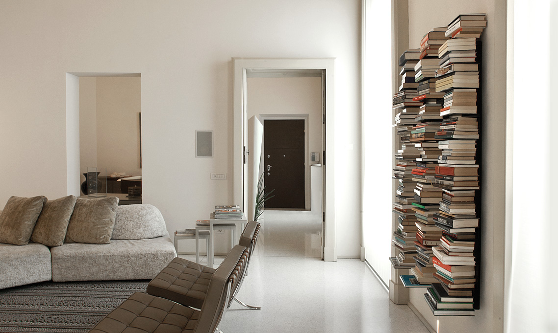 Ptolomeo Wall vertical wall-mounted bookcase by Opinion Ciatti in matte black steel, featuring C-shaped shelves that appear to levitate books, displayed in Royal Oak, Michigan showroom.