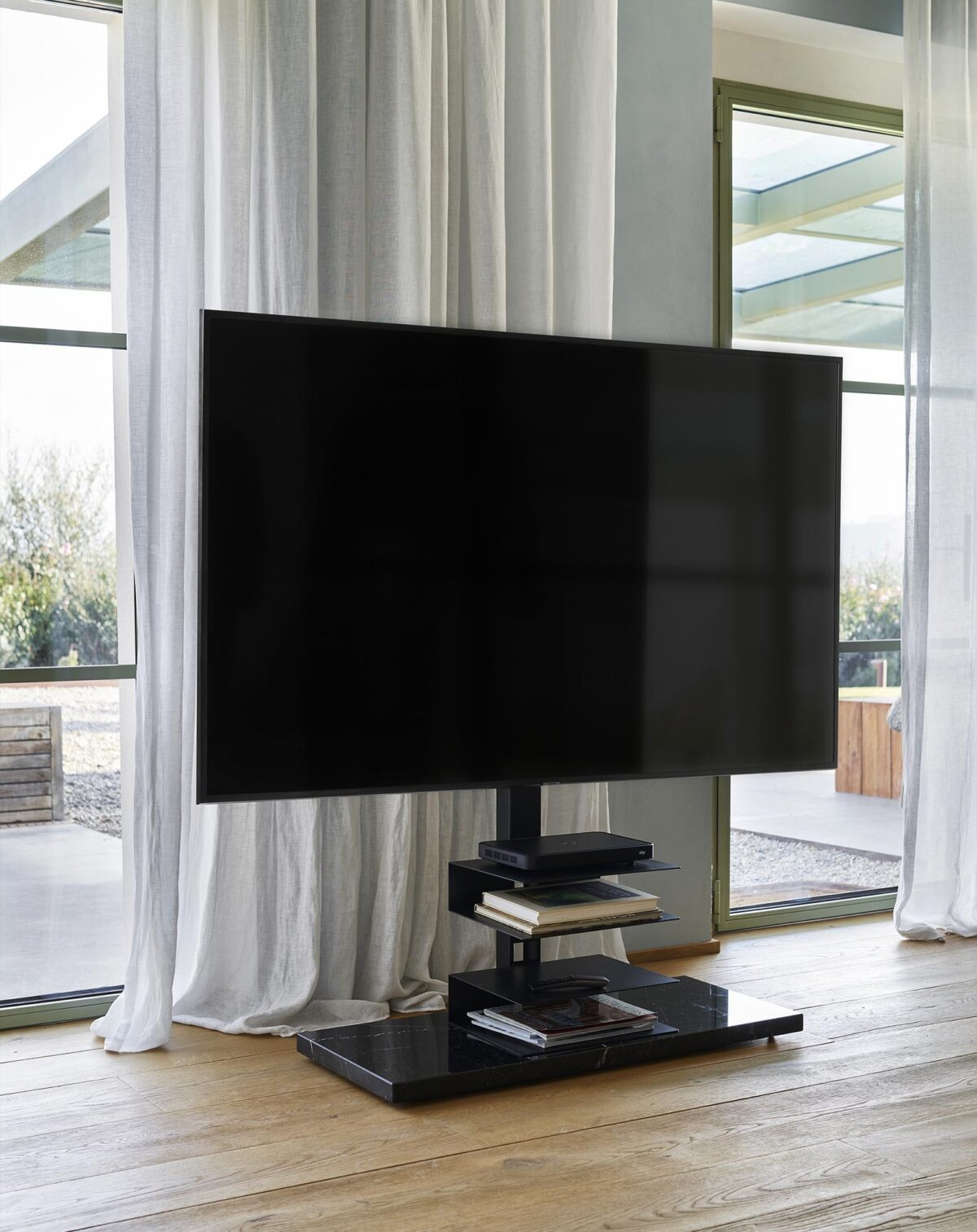 Ptolomeo TV Smart by Opinion Ciatti in matte black steel with pivoting wheels and steel shelves, supporting TVs from 43 to 82 inches, displayed in Royal Oak, Michigan showroom.