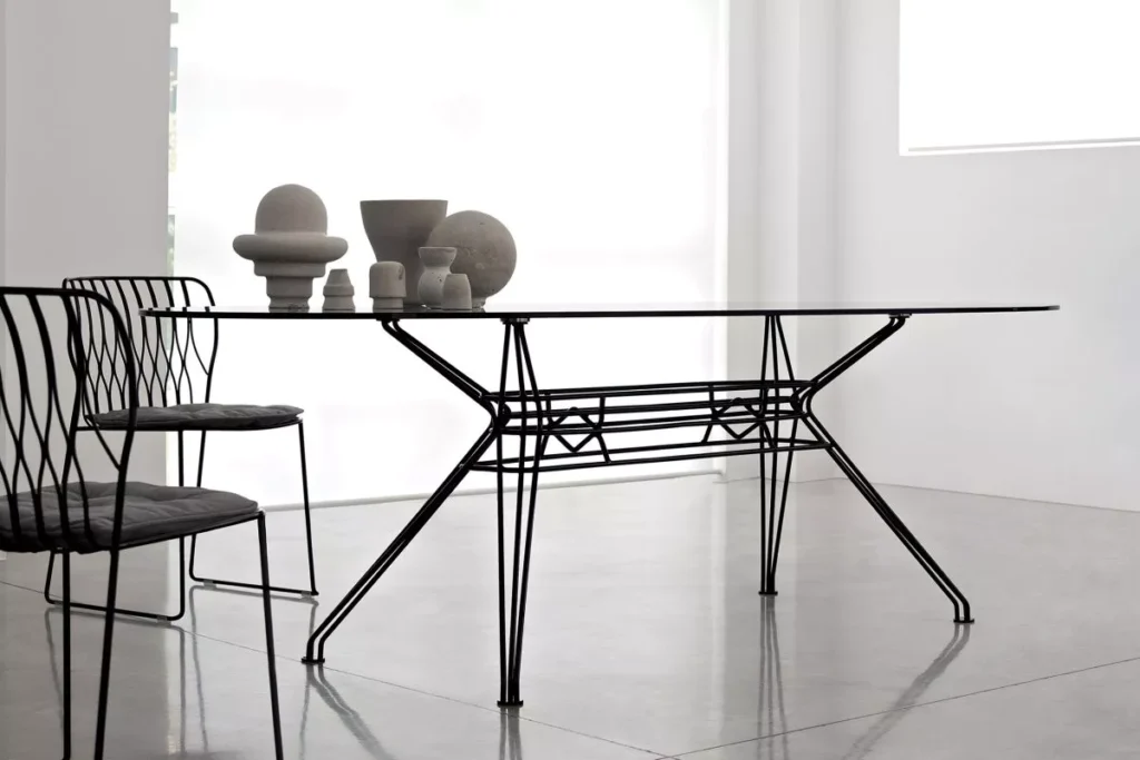 Sander Outdoor dining table by Bontempi Casa with white lacquered metal frame and transparent extra‑clear glass top on a garden terrace.