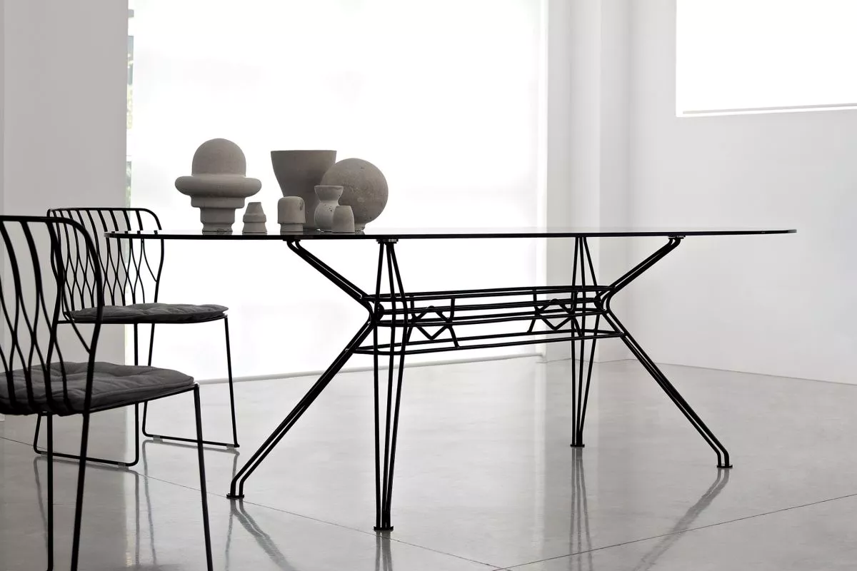 Sander Outdoor dining table by Bontempi Casa with white lacquered metal frame and transparent extra‑clear glass top on a garden terrace.