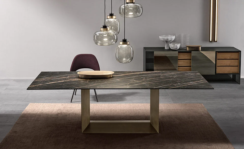 T5 E extendable dining table by Tonelli Design with central base in brushed bronze finish, top and extensions in polished Calacatta oro venato ceramic, displayed in Royal Oak, Michigan.